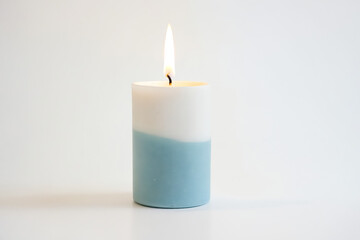 Canvas Print - Blue and White Candle Burning on White Background