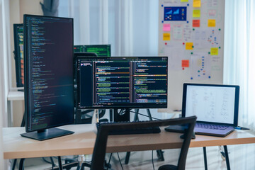 Wall Mural - software development office workstation setup with multiple monitors displaying code and development