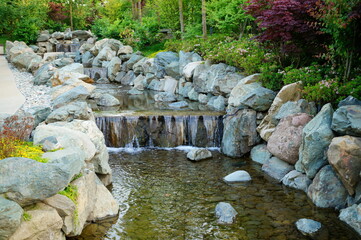 Poster - A garden stream with a small waterfall. There are a lot of big rocks around. Parks and nature.