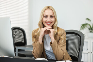 Wall Mural - Portrait of happy secretary at table in office