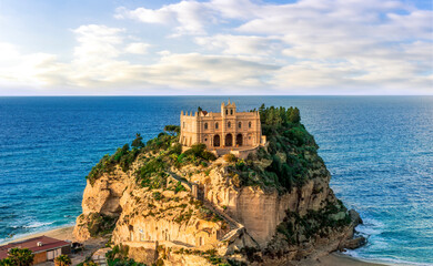 sea landscape of beautiful white temple or castle on a high cliff isle on a rock in crystal clear turquoise sea with waves and beautiful sunset or sunrise on background of seascape