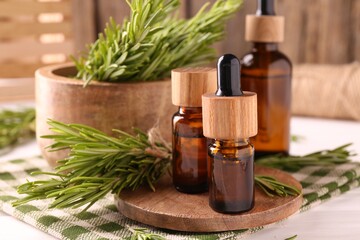 Wall Mural - Essential oil in bottles and rosemary on white wooden table, closeup