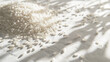 © Jakraphong - Rice Grains Spread on White Background with Strong Lighting, Emphasizing Texture and Shape