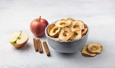 Wall Mural - Homemade dried apples with cinnamon, apple chips in a bowl with cinnamon sticks on a light gray background. Delicious healthy snack