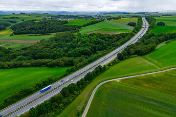 Wall Mural - blue cargo truck on the highway. asphalt road among green fields and beautiful clouds. cargo delivery and transportation concept