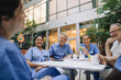 © Maskot - Happy male and female doctors sitting at table in cafeteria of hospital