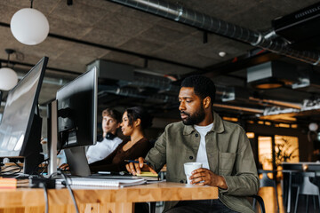 Male computer programmer working while sitting at tech start up office