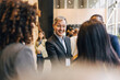© Maskot - Happy senior male entrepreneur talking with delegates during networking event at convention center