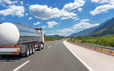 Fuel truck on a picturesque road. A silver tank truck transports fuel.