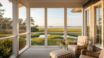 Charming covered porch with striped chairs and ottoman overlooking scenic marshland and Morris Island in Beaumont, South Carolina. Wood-paneled walls and white ceiling with large windows open to ocean