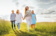 © Soloviova Liudmyla - Portrait of four cheerful smiling women holding hand in hand walking by a high green grass meadow. They looking at the camera. Woman's friendship, relations, and happiness concept image.