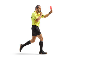 Full length profile shot of a football referee running and showing a red card