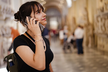 Cute teen girl using an audio guide in a museum smiling