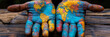 © Cristian - two hands holding a world map painted in colors, the hands are on a wooden table