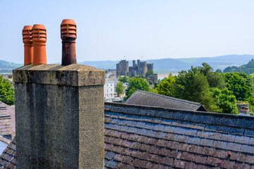 Wall Mural - Rooftop chimney view over Conway Wales with medieval castle and dense green trees under a clear blue sky