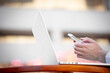 © pathdoc - Closeup image of woman hands holding, using smart, mobile phone and laptop computer outdoors