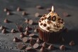 © Ibraheem - A cupcake with a number 40 candle, surrounded by chocolate chips, on a solid dark dark chocolate background.