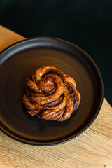 Wall Mural - A cinnamon or cardamom bun on black plate