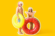 © Pixel-Shot - Young couple with inflatable rings and Santa hats on color background