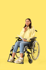 Sticker - Thoughtful young woman in wheelchair with notebook on yellow background