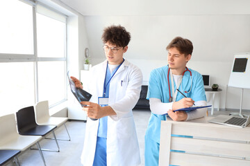 Wall Mural - Male medical interns examining x-ray scan of lungs at reception in clinic