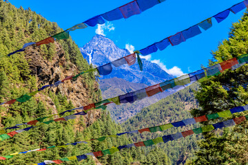 Colorful Nepali and Tibetan prayer flags fluttering in the majestic mountains of Nepal. Symbolizing peace, compassion, and blessings, flags adorn the serene landscape of Himalaya mountains