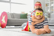 © Pixel-Shot - Little boy with his father in superhero costumes lying on floor at home