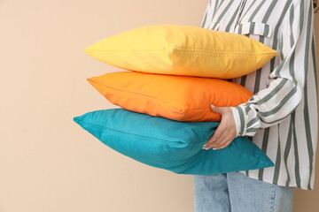 Wall Mural - Woman with bright pillows on beige background, closeup