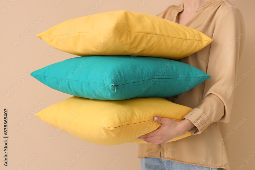 Woman with bright pillows on beige background, closeup