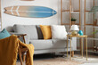 © Pixel-Shot - Light interior of living room with comfortable sofa, coffee table, shelving unit and surfboard
