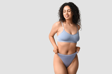 Wall Mural - Beautiful young happy African-American woman in stylish underwear on grey background