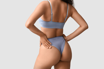 Wall Mural - Beautiful young African-American woman in stylish underwear on grey background, back view