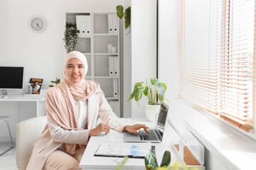 Poster - Beautiful Muslim businesswoman working with laptop at desk in office