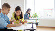 © Home-stock - Schoolgirl sitting at desk near boy, girl pointing in copybook of friend with finger and smiling, enjoying learning process in classroom, panorama, free space