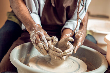 Hands of two people making a new pottery product together