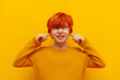 © Богдан Маліцький - annoyed red-haired teenage boy covers his ears with his hands and does not listen on a yellow isolated background, a dissatisfied child with an orange hairstyle ignores and avoids