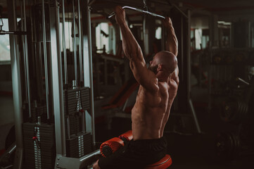 Wall Mural - Caucasian man doing lat pull-downs on a machine. 