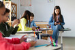© Home-stock - Focused schoolchildren using cellphones while sitting at desks in school classroom interior during break, copy space