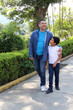 © Arlette - Divorced single dad walks in the park with his 10 year old dark latin son spend quality time together have fun and celebrate Father's Day