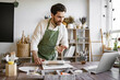 © sofiko14 - Man rolls clay with rolling pin in a bright and cozy pottery studio. He is concentrated on his work, surrounded by various pottery tools and equipment, creating a relaxed and creative atmosphere.