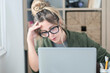 © simona - Sad and frustrated young woman feeling tired and worried about a problem sitting at desk with laptop, stressed and in pain female having problems reading bad news online, email notification about debt