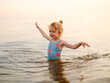 © Cavan Images - Funny little girl child splashing in lake water in summer