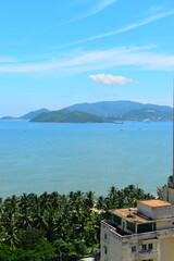 Wall Mural - Nha Trang city, Vietnam - October 15, 2023 : Overlooking the beautiful coast of Nha Trang with palm trees on the beach with deck chair and parasol. Beautiful white sand tropical beach in coastal city.