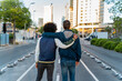 © tunedin - Rear view of two men embracing on the street in the city, Barcelona, Spain