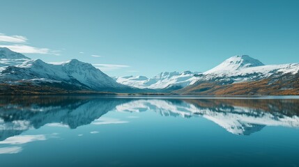  A serene lake reflecting snow-capped mountains under a clear blue sky.