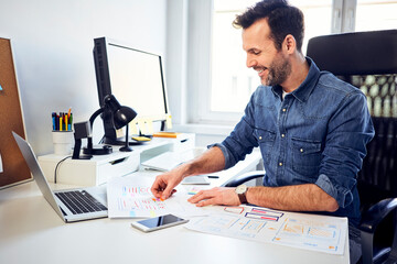 smiling web designer working on draft at desk in office