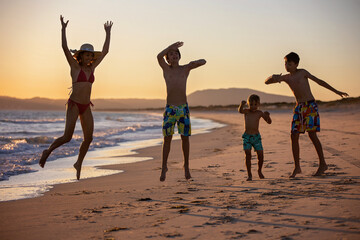 Wall Mural - Happy children, boys, playing on the beach on sunset, kid cover in sand, smiling, laughing