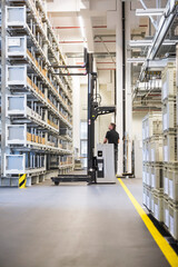 Canvas Print - Worker operating forklift in factory warehouse