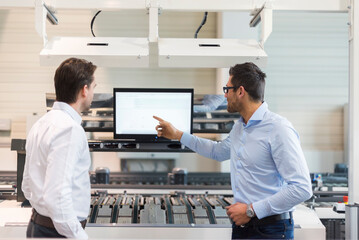 Canvas Print - Two businessmen talking at screen in modern factory