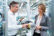 © tunedin - Businesswoman and man talking at assembly robot in a factory